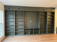 an empty living room with built - in bookcases and hard wood flooring