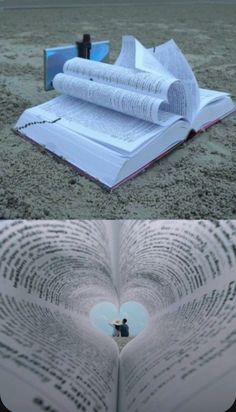 an open book laying on top of a sandy beach next to a heart shaped hole