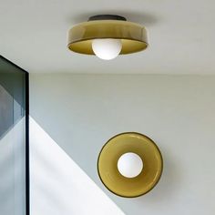 two circular lights hanging from the ceiling in a room with white walls and flooring