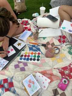 a woman sitting on top of a quilt covered ground next to other people working on crafts