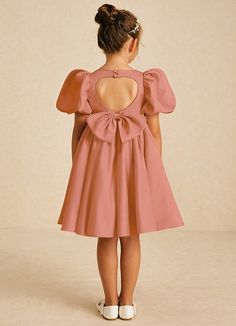 Muffin showcases a charming A-line shape in matte satin, featuring a stylish square neckline and a convenient zipper closure adorned with covered buttons. Finished with lovely bows, this dress is a delightful blend of elegance and whimsy for any young bridesmaid. Pink A-line Dress With Bow, Party Dress With Bow Tie Back And Square Neck, Pink Puff Sleeve Dress With Bow, Pink Square Neck Dress With Tie Back, Chic Dress With Bow Detail, A-line Fitted Dresses With Detachable Bow, Puff Sleeve Dress With Bow For Party, Fitted A-line Dresses With Detachable Bow, Fitted A-line Dress With Bow Straps