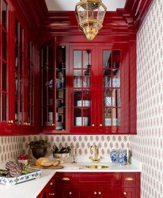 a kitchen with red cabinets and white counter tops, gold trim on the door knobs