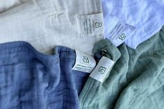 four different colored linens with tags on them are laying next to each other in rows