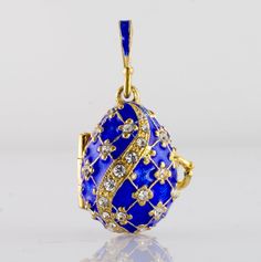 "Sterling silver 24K gold plated egg shaped locket, enameled on both outside and inside with the guardian angel surprise charm, designed and made in our NJ shop. Royal blue enamel covers the surface of the pendant, and Swarovski crystals are set at the center of the tiny 4-petal flowers of the outside design. The egg is 20 mm (0.9\") long without a bail for a chain. The pendant will come with 18\" sterling silver gold plated chain and in a gift box. We make this locket in a variety of colors, wi Oval Enamel Locket Jewelry, Luxury Oval Locket Necklace As Gift, Luxury Oval Pendant Locket Necklace As Gift, Blue Enamel Locket Jewelry, Elegant Enamel Jewelry Keepsake, Enamel Locket Jewelry For Gifts, Oval Enamel Jewelry For Gift, Collectible Oval Pendant Charms Jewelry, Collectible Enamel Jewelry With Oval Pendant