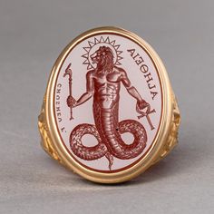 Chnoubis, a revered Gnostic deity and guardian demon, is exquisitely engraved onto carnelian in this piece. Historically cherished, this motif has graced gems, amulets, and talismans, offering protection against malevolent spirits and energies. This symbol doesn't just serve as a testament to ancient beliefs and practices but offers the wearer a sense of safety, grounding, and connection to age-old wisdom. Materials: Carnelian intaglio set in a solid 18K gold signet ring Measurements: Approximat Spiritual Yellow Gold Signet Ring, Spiritual Engraved Signet Ring For Ceremonial Occasions, Spiritual Engraved Signet Ring For Ceremonial Use, Spiritual Gold Engraved Gemstone Ring, Symbolic Gemstone Signet Ring As Gift, Spiritual Oval Signet Ring Collectible, Spiritual Yellow Gold Engraved Oval Ring, Symbolic Yellow Gold Engraved Ring With Intaglio, Spiritual Oval Engraved Yellow Gold Ring