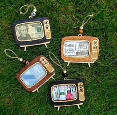 four miniature tvs are sitting on the grass and one has a dollar bill in it