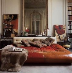 a bedroom with a large mirror above the bed and leather furniture in front of it