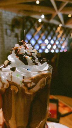 someone is holding up a chocolate milkshake with whipped cream and chocolate shavings