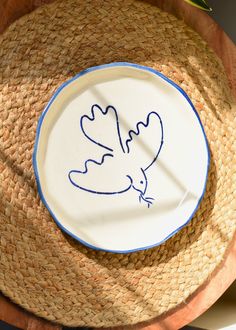 a plate with a bird drawn on it and a straw hat next to the plate