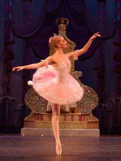 a young ballerina is dressed in pink and white