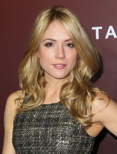 a woman with long blonde hair wearing a black and gold dress