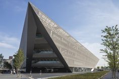 a large triangular building sitting on the side of a road next to trees and bushes