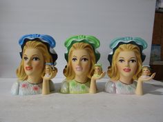 three ceramic figurines with hats on their heads, one holding a small doll