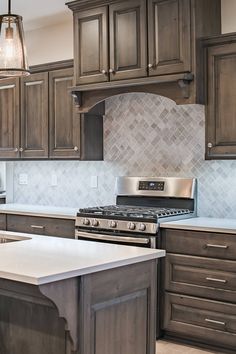 a kitchen with wooden cabinets and white counter tops, an island in front of the stove