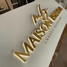 the name madison is illuminated in gold letters on a white table with chairs and tables behind it