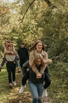 group of people walking down a path in the woods with their arms around each other