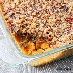 a casserole dish filled with sweet potato casserole topped with pecans