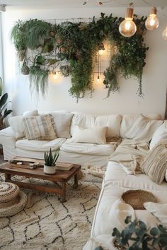 a living room filled with lots of white furniture and plants on the wall above it