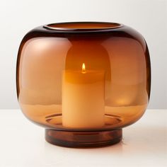 a brown glass vase with a lit candle inside