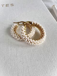 The subtle luster of the ivory pearl beads pairs harmoniously with the warm glow of the gold beads, creating a sophisticated and timeless design. Perfect for both casual and formal wear, these beaded hoop earrings will add a touch of elegance to any outfit.  Earring hoop and closure made with 18K gold plated 304 stainless steel. **Each of my earrings are delicately handwoven bead by bead. I absolutely love making these and want you to know that each piece is made with patience and care from start to finish! These earrings are made with size 11/0 and 15/0 seed beads and Miyuki Japanese Delica beads. I use strong nylon thread to ensure the integrity of each earring.** Earring Hoop, Ivory Pearl, Delica Beads, Beaded Hoop Earrings, Beaded Hoops, Gold Beads, Pearl Beads, Formal Wear, Jewelry Earrings Dangle