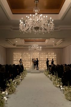 wedding ceremony setup with chandelier and white flowers on the aisle, surrounded by candles