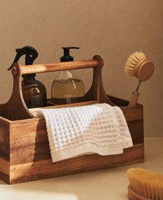 a wooden holder with soap, toothbrush and lotion in it on a table