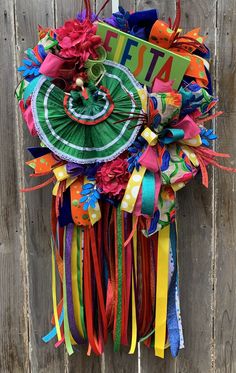 a colorful tie hanging on the side of a wooden fence next to a sign that says fiesta