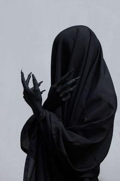 a person in a black cloak with their hands out to the side, holding two fingers up