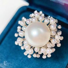 a white pearl and diamond ring in a blue velvet case on top of a table