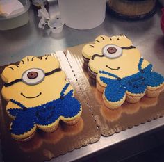 two yellow cupcakes with blue frosting are on top of a metal counter