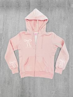 Meet the Bow Zip Up from Sassy Shortcake! This baby pink sweatshirt is adorned with a playful white bow and the text sassy shortcake, bringing a touch of coquette charm to your outfit. She is fleece lined, and she features a hood and a split kangaroo pocket. She is soft, lightweight, and absolutely adorable! Also available in three other pink shades. Oversized fit + unisex sizing. Model is wearing a size small. Pink Sweatshirt For Loungewear, Cute Zip Up Hoodie Pink, Baby Pink Bow, Cute Pink T-shirt With Bow, Pink Short Sleeve T-shirt With Bow, Pink Gold-plated Charm Necklaces With Adjustable Chain, Pink Crew Neck T-shirt With Bow, Sassy Shortcake, Patriotic Dresses