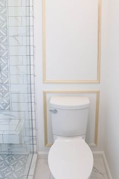 a white toilet sitting in a bathroom next to a walk - in shower stall and tiled floor