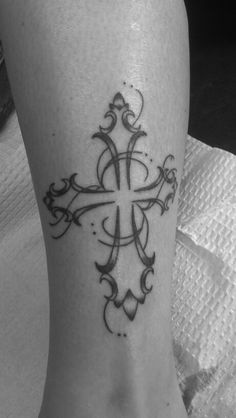 a black and white photo of a foot with a cross tattoo design on it's side