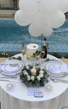 a table set up with white flowers and balloons