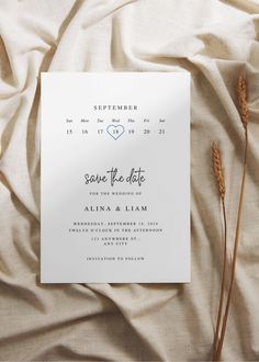 the save the date card is next to some dried flowers on a bed sheet with white sheets