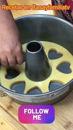 a person is pouring yellow liquid into a cake pan with hearts on the inside and bottom