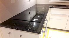 an empty kitchen with black counter tops and white cabinets in the back drop off area