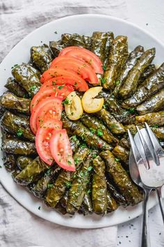 a white plate topped with grilled artichokes covered in tomatoes and herbs