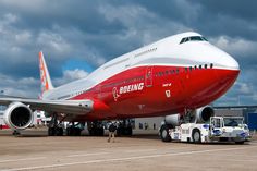 an airplane is parked on the tarmac with other vehicles around it and people standing outside