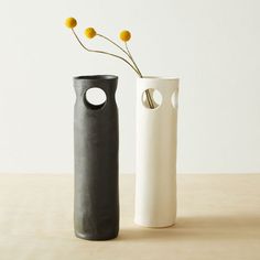 two black and white vases with yellow flowers in them