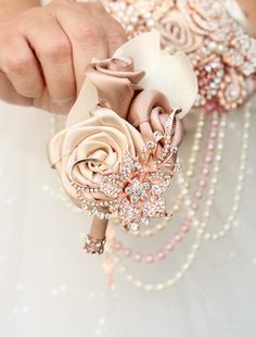 a woman in a wedding dress holding a flower brooch with pearls on the side