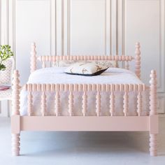 a pink bed with white sheets and pillows