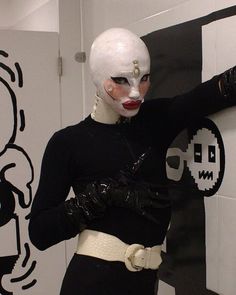 a woman dressed in white and black poses with her hands on her hips while wearing a mask