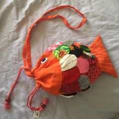 an orange fish shaped purse on a white sheet