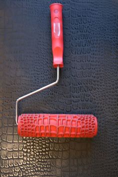 a red handle is attached to a black surface with an orange stick on it and a white object in the background