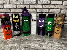 five halloween candles are lined up on a table with brick wall in the back ground