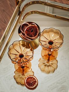 three glasses with blood oranges in them sitting on a glass tray next to a mirror