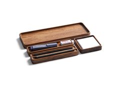 a wooden pen holder with two pens and a notepad in it on a white background