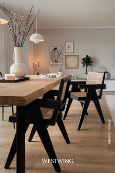 a dining room table with chairs and vases on it's side, in front of a window