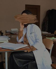 a woman sitting at a desk with her hair in the air over her head, covering her face